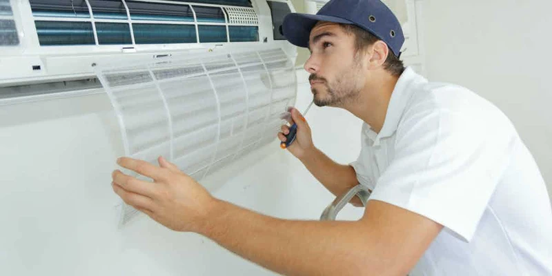 Technician inspecting and servicing residential cooling equipment