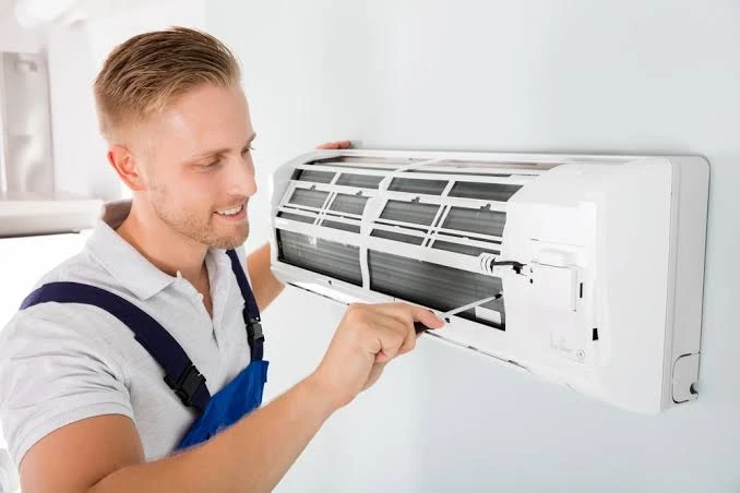 Technician adjusting digital climate control sensor and indoor blower