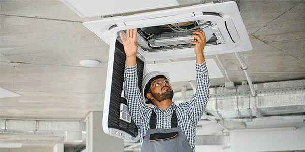 Technician installing a residential ceiling air conditioning cassette unit