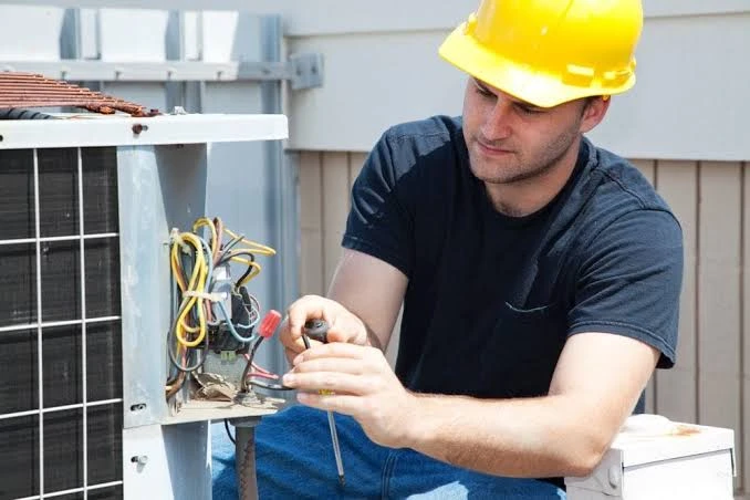 HVAC technician testing electrical connections on outdoor heating system