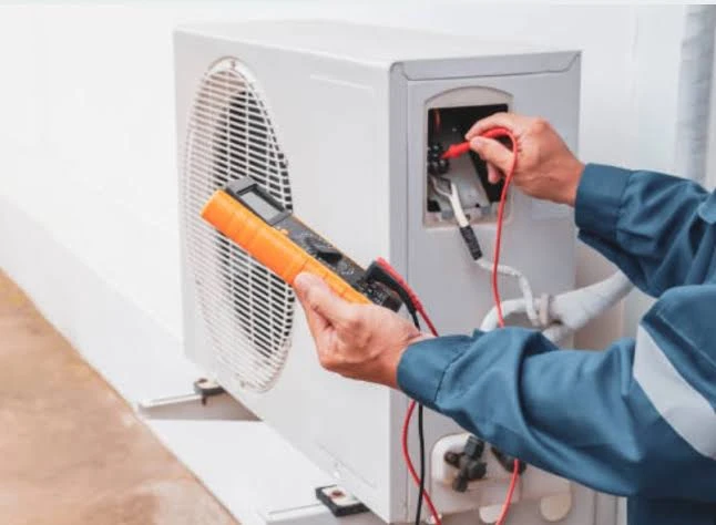 HVAC specialist troubleshooting heating system electronics with a multimeter